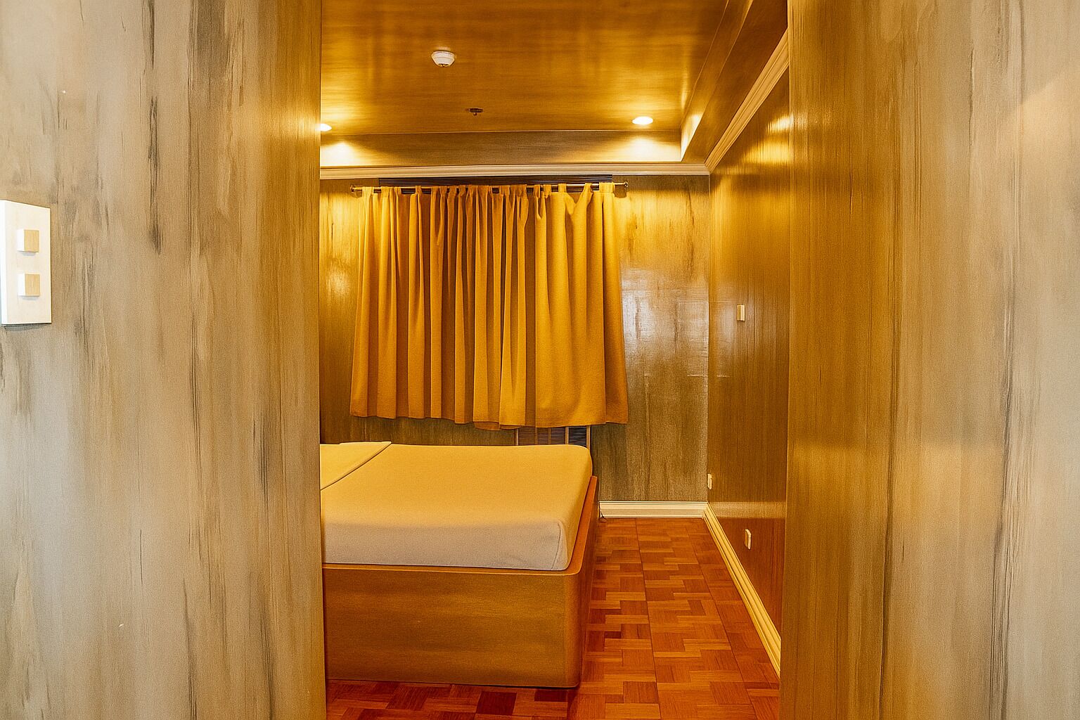 Una camera d'albergo con pavimento in legno, un letto e una tenda.