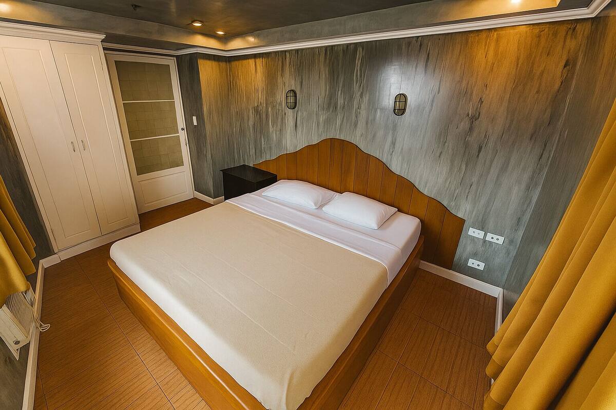 A bedroom with a wooden headboard, a bed with white linens, a nightstand, and a wardrobe.