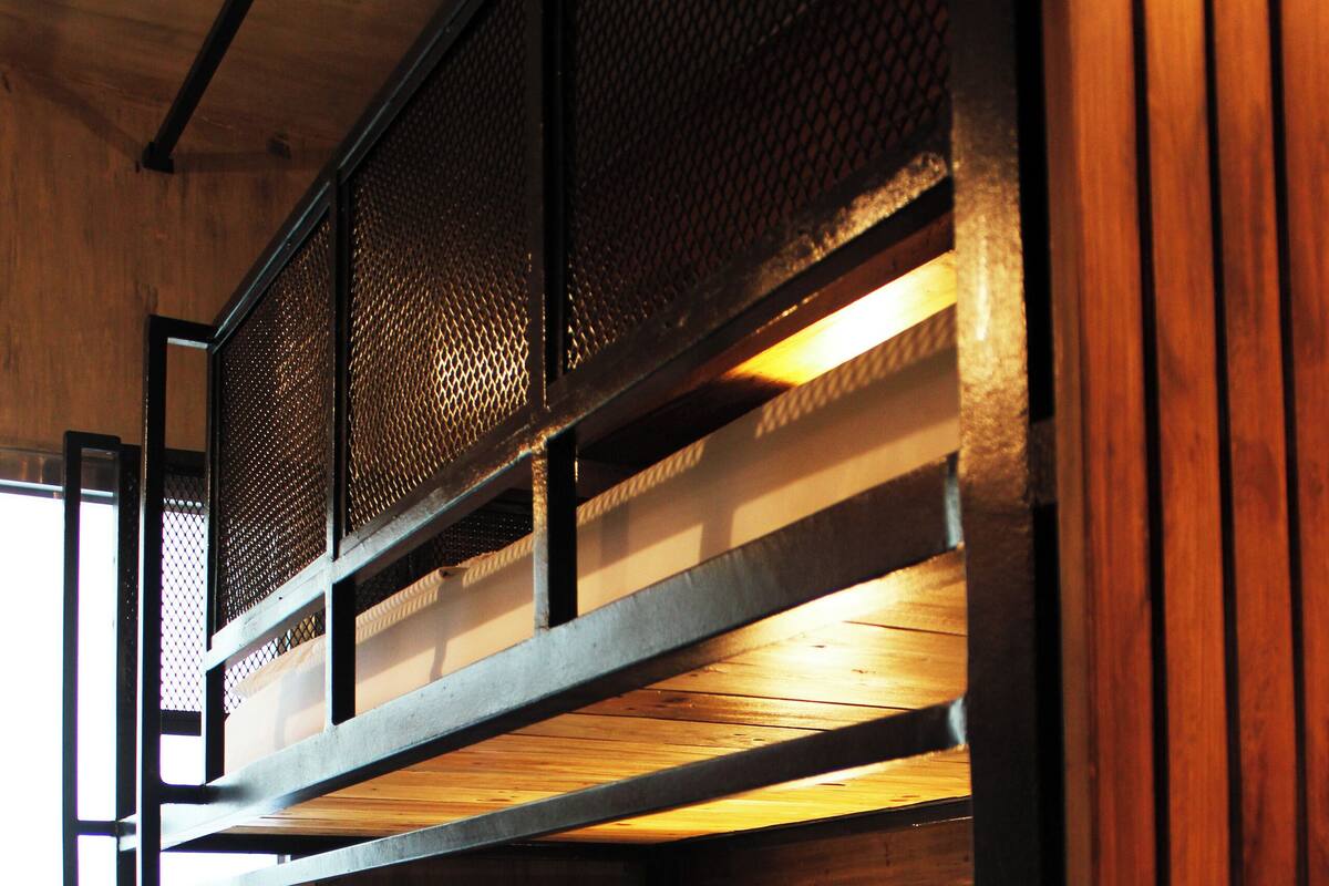 A bunk bed with a wooden headboard and a wall-mounted light fixture.
