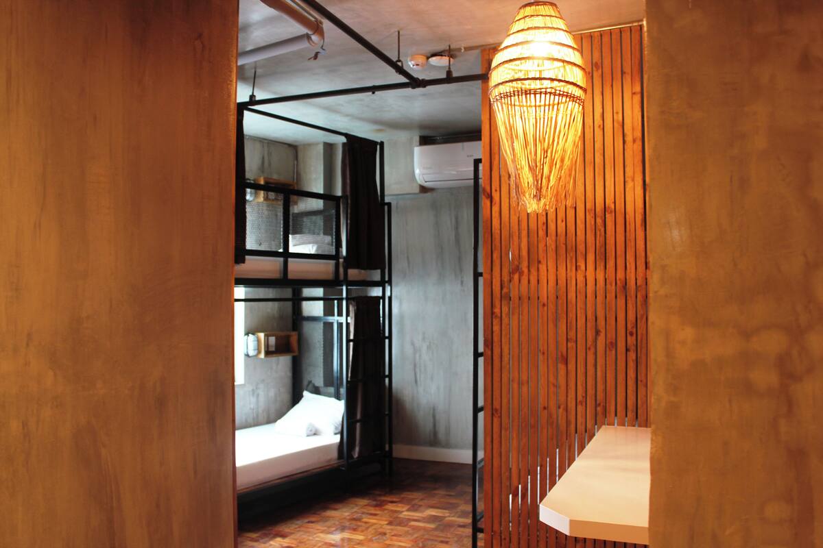 A modern room with a bunk bed, a hanging light fixture, and a wooden partition.