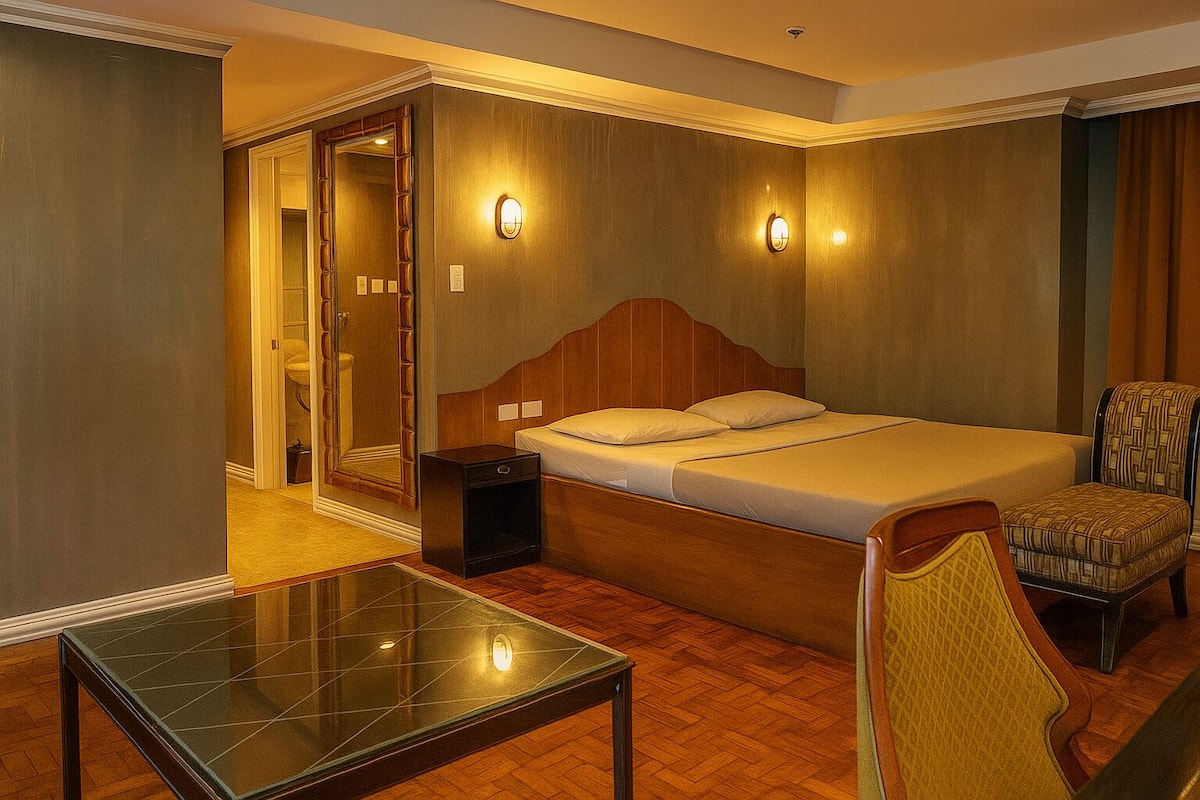 A hotel room with a wooden bed, a nightstand, a chair, and a glass table.