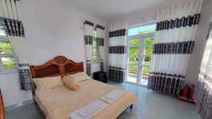 Ein Schlafzimmer mit einem hölzernen Bett, beigefarbener Bettwäsche und Vorhängen mit einem schwarz-weißen Muster.