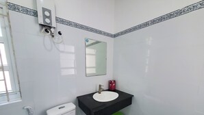 Ein Badezimmer mit Toilette, Waschbecken, Spiegel und Toilettenpapierhalter.