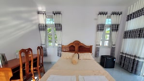 Ein ordentlich eingerichtetes Schlafzimmer mit Bett, Holz-Kopfteil und Vorhängen.