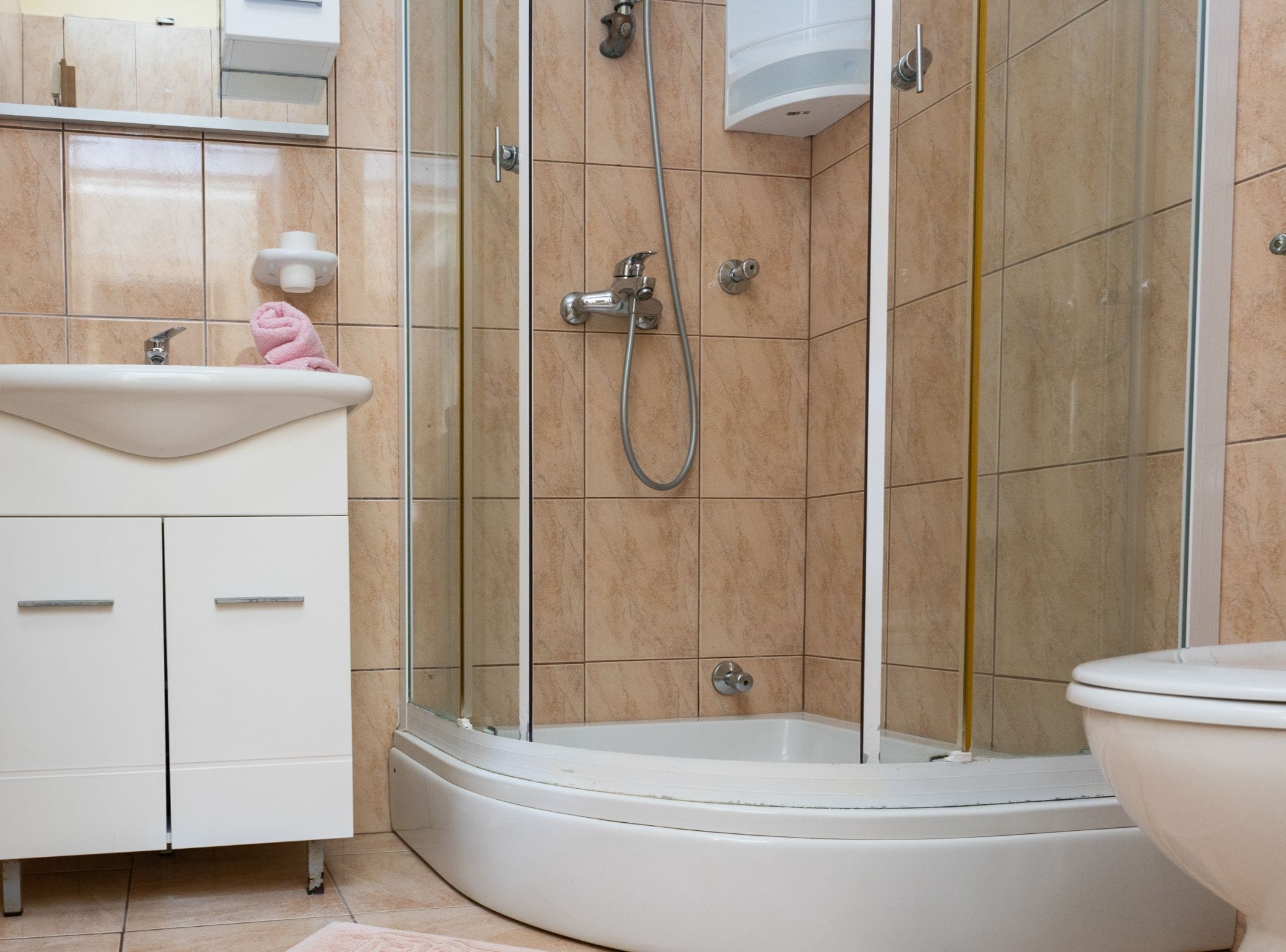 Un baño moderno con ducha de vidrio, un lavamanos blanco y un inodoro.