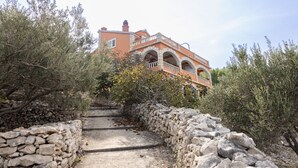 A stone staircase leading to a multi-story building with arches and balconies, surrounded by olive trees and shrubs. - Apartments Sea Line (Blato)