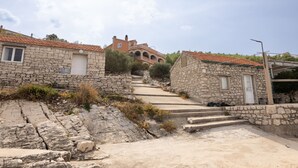 A stone building with a tiled roof, a stone staircase leading to a higher level, and a clear sky. - Apartments Sea Line (Blato)