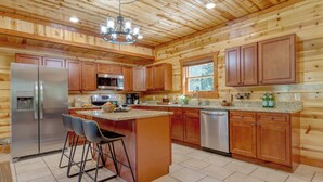 A spacious kitchen with wooden paneling, stainless steel appliances, and a central island with bar stools.