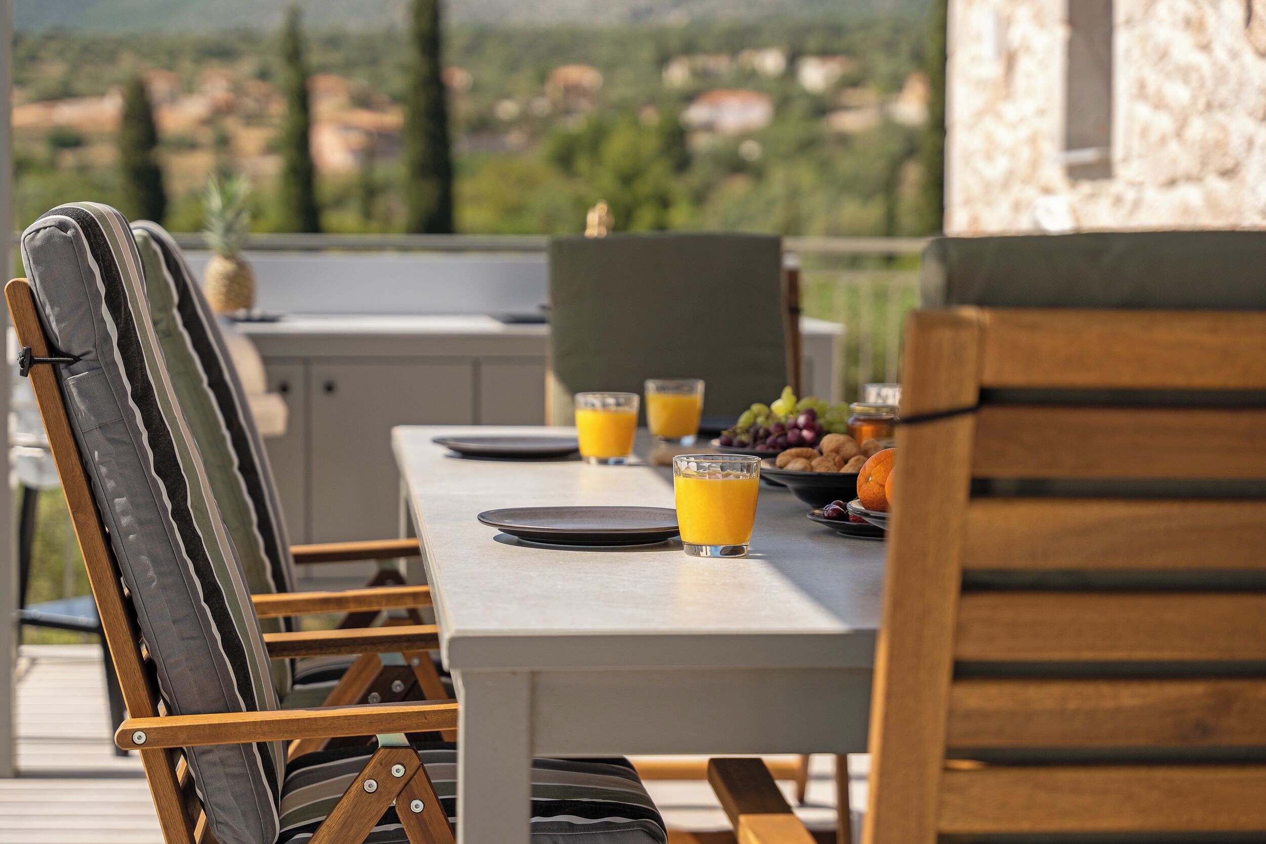 A dining table with chairs, a pineapple, and a glass of orange juice.