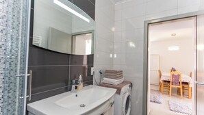 A modern bathroom with a large mirror, a sink, and a washing machine. - Apartment Mojaš (Dubrovacko Primorje)