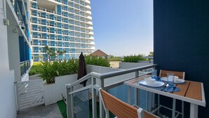 Un balcón con una mesa dispuesta para comer, con vistas a un edificio de varios balcones y un cielo despejado.