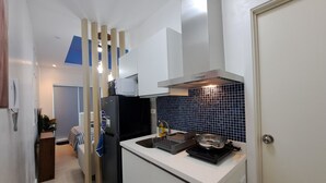 Cocina compacta con microondas, estufa y refrigerador negro.