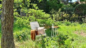 Een tuin met een witte stoel en tafel, omringd door groen en bloemen.