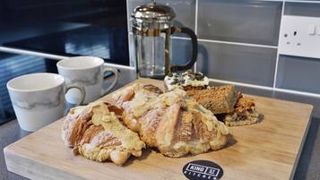 Una tabla de madera con pasteles y una cafetera en una cocina.