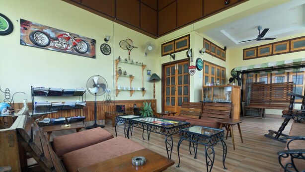 Ein geräumiges Zimmer mit Holzeinrichtung, einem Deckenventilator und einem Motorradbild an der Wand.
