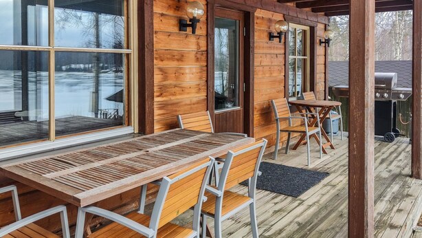 A wooden deck with a table and chairs, a grill, and a covered area with windows. - Haaparanta by Interhome (Ruovesi)