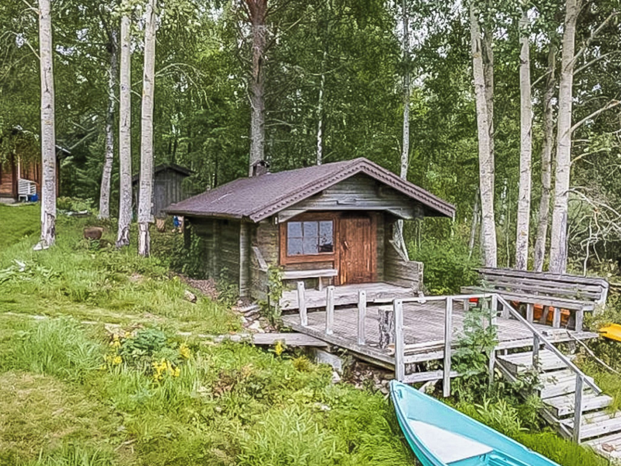 Mökki, jossa on puinen terassi ja jonka ympärillä on puita.