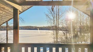 A wooden gazebo with a view of a frozen lake and trees.