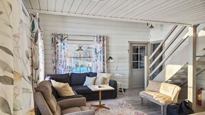 A living room with a sofa, armchair, and a small table. There is a staircase to the right and a door leading outside. - Haaparanta by Interhome (Ruovesi)