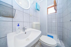 Een badkamer met een wit wastafel, toilet en douche.