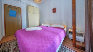 Een slaapkamer met een bed, een kledingkast, een nachtkastje en een hanglamp.