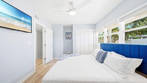 A bedroom with a bed, a ceiling fan, a window with a view, and a door leading to another room. - Entire Resort, The Siesta Key Bungalows, 1-Mile to Turtle Beach (Siesta Key)