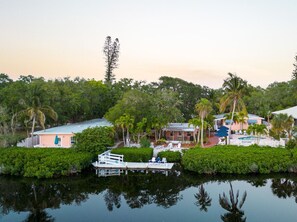 Uma propriedade à beira-mar com um píer, piscina e vários edifícios, tudo envolto em vegetação exuberante.