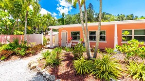 A single-story building with a red exterior, surrounded by a variety of tropical plants and palm trees. - Entire Resort, The Siesta Key Bungalows, 1-Mile to Turtle Beach (Siesta Key)