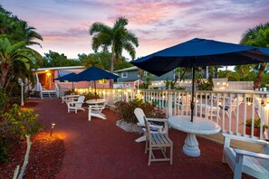 A patio area with outdoor seating, umbrellas, and a pool in the background. - Heated Pool, Dock, Kayaks, on Lagoon, Turtle Beach 1-mile & Crescent Beach 2-miles, 3-units (Siesta Key)