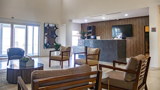 Una hall moderna con arredi in legno, una reception e un'ampia finestra.