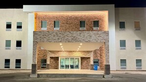 Un edificio moderno con facciata in mattoni, grande ingresso in vetro e numerose finestre.