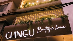 A multi-story building with balconies adorned with plants. The sign "CHINGU Boutique home" is prominently displayed.