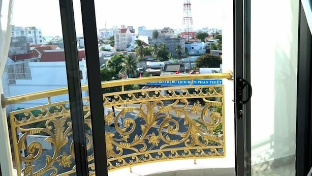 A balcony with a view of a cityscape, including buildings and a tower. - Ha Anh Phan Thiet Hotel (Phu Thuy)