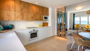 A modern kitchen with white cabinets, a microwave, and a wooden accent wall.