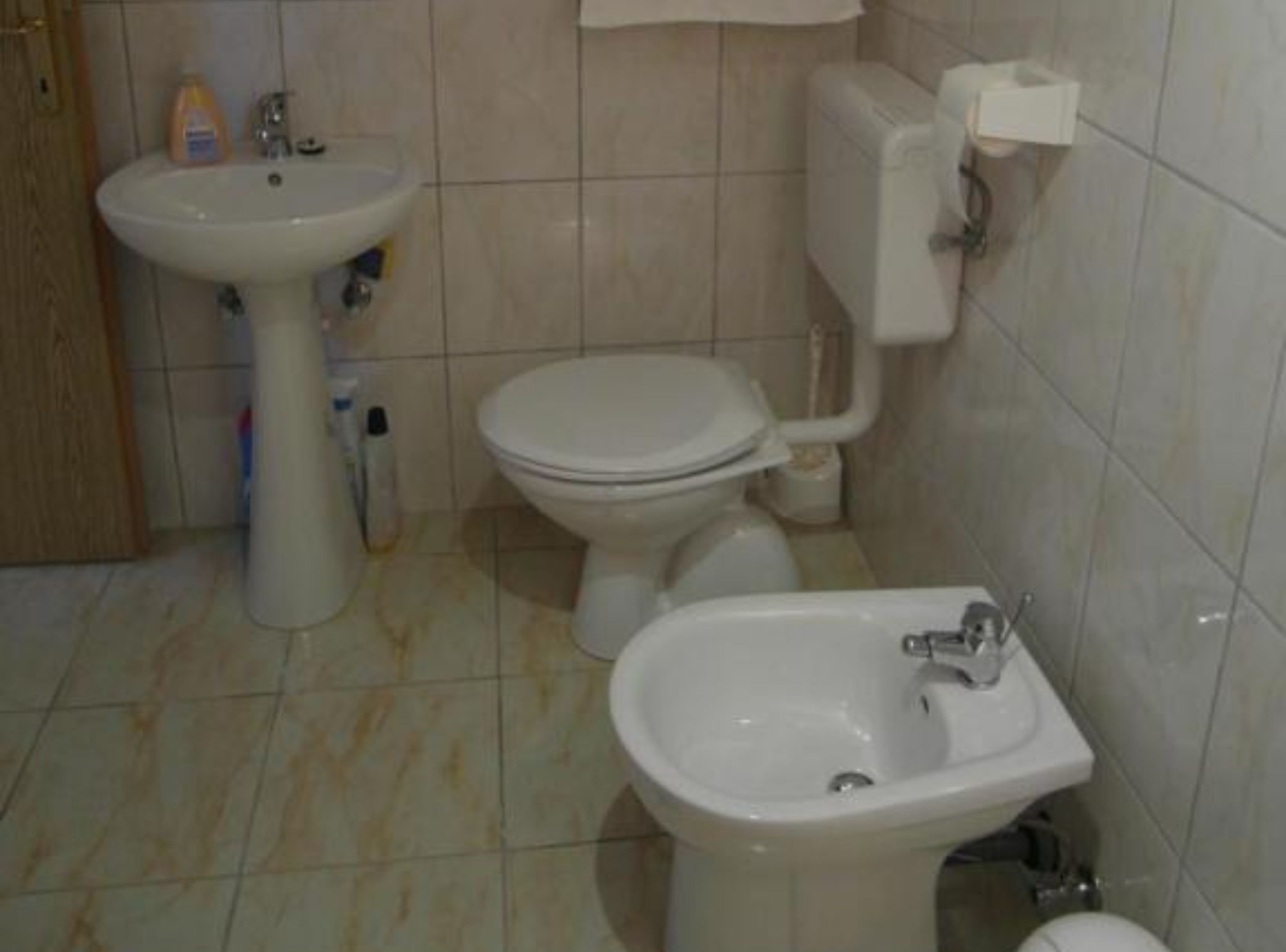 A bathroom with a sink, toilet, and bidet.