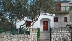 A stone-walled building with a red door and a green gate, leading to a staircase. - Apartment Antonio (Bilice)