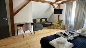 A room with a bed, a desk, a chair, a sofa, and a TV.