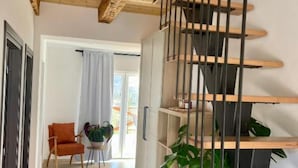 A modern interior with a wooden staircase, a dining area with a table and chairs, and potted plants.