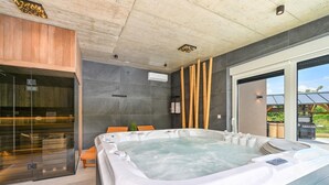 Et moderne badeværelse med et stort badekar, et glasbadekar og en træbænk.