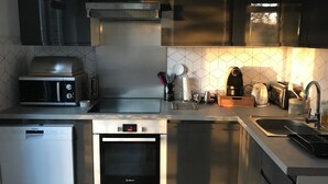 Moderni keittiö, jossa on Bosch-uuni, Siemens-mikroaaltouuni, integroidtu astianpesukone ja kahvinkeitin.