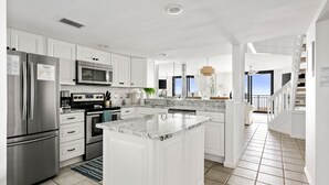 Une cuisine moderne avec des meubles blancs, des appareils en acier inoxydable et un grand îlot central.