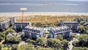 Un hôtel situé en bord de mer, composé de plusieurs bâtiments, doté d’une piscine et offrant une vue sur la plage.