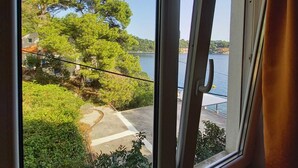 Ein Fenster mit Blick auf einen See, Bäume und ein Gebäude im Hintergrund.