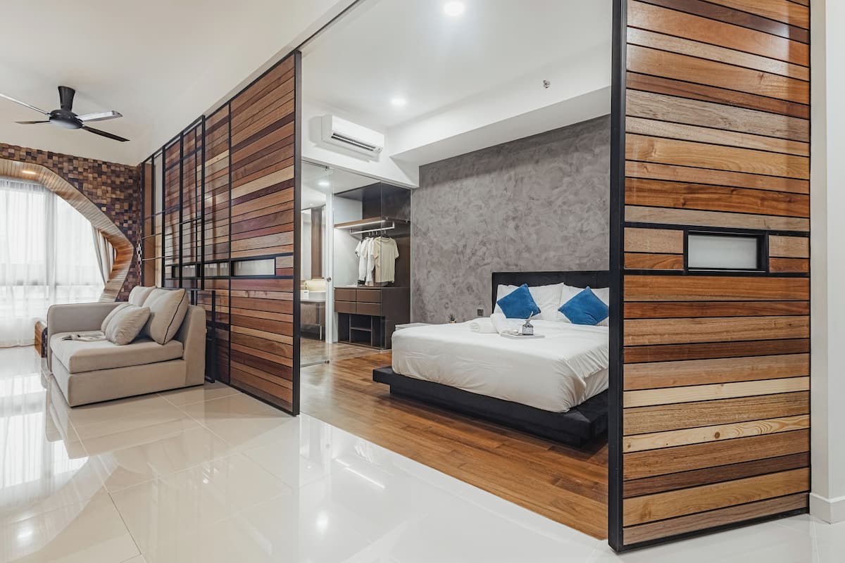 Une chambre à coucher moderne avec un mur recouvert de panneaux en bois, un lit avec des coussins bleus, un canapé et un dressing.