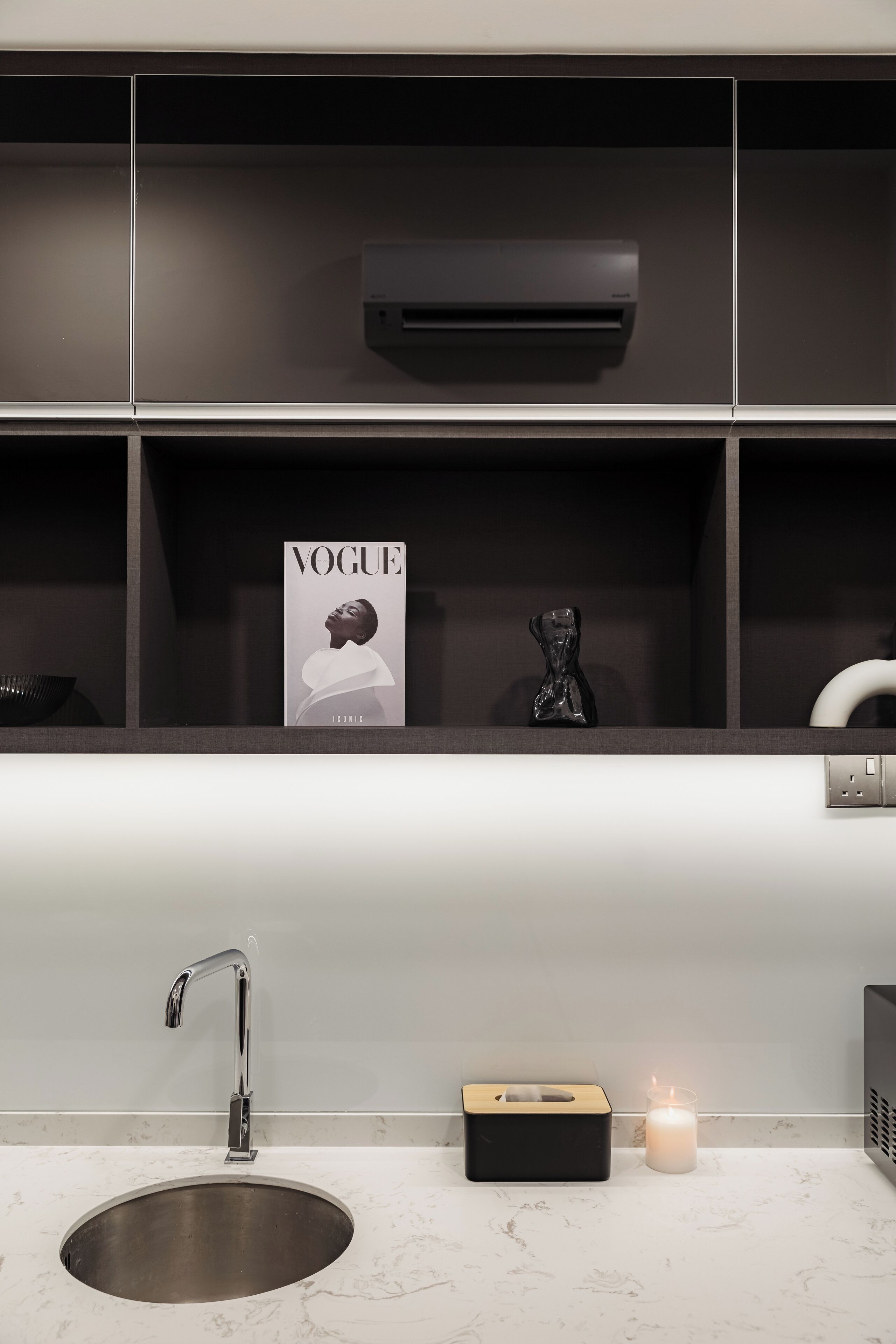 A modern kitchen with a built-in sink, a magazine rack, and a small statue.