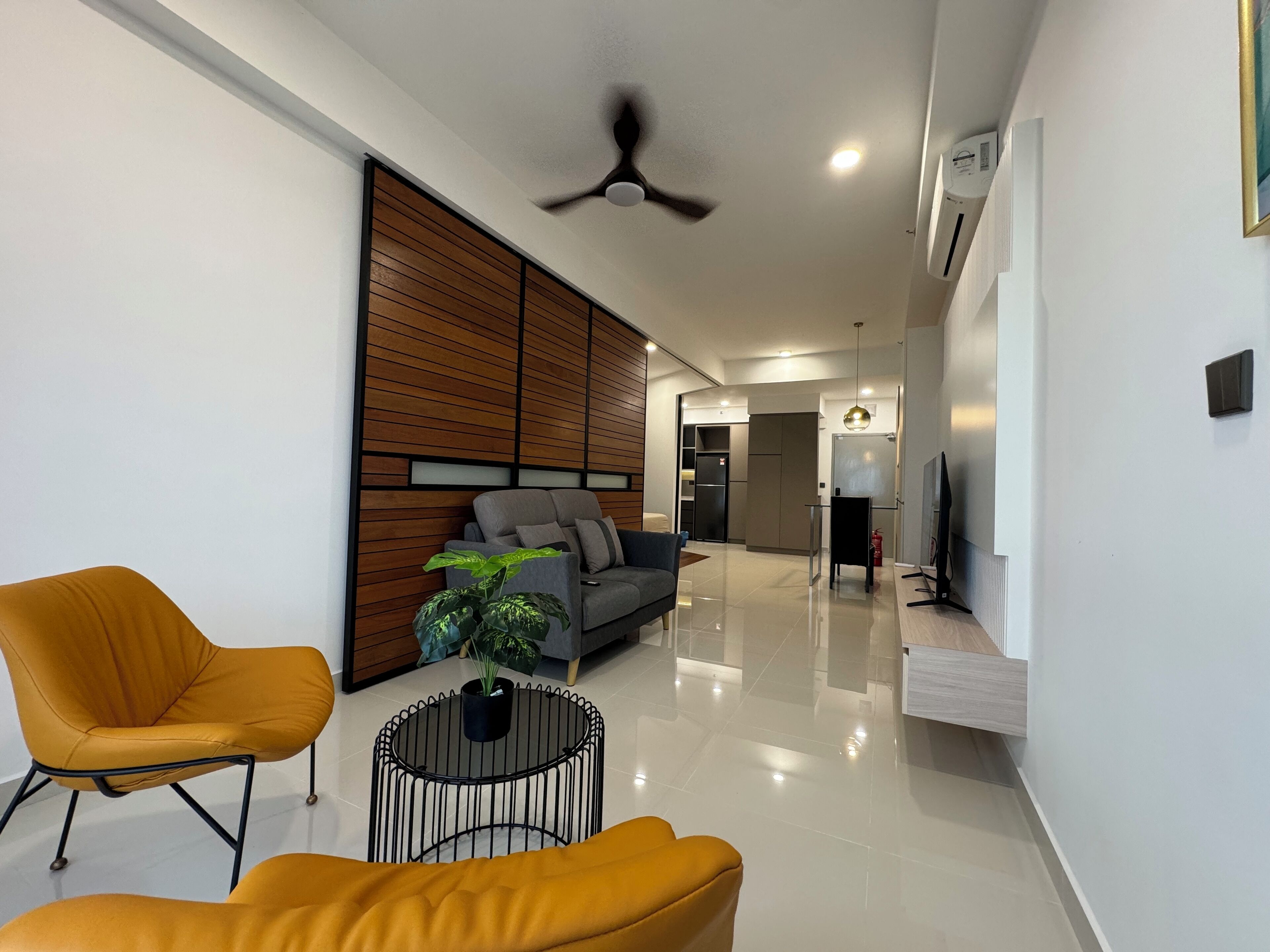 Uma sala de estar moderna com um sofá, duas poltronas amarelas, uma mesa de centro e uma planta em vaso.