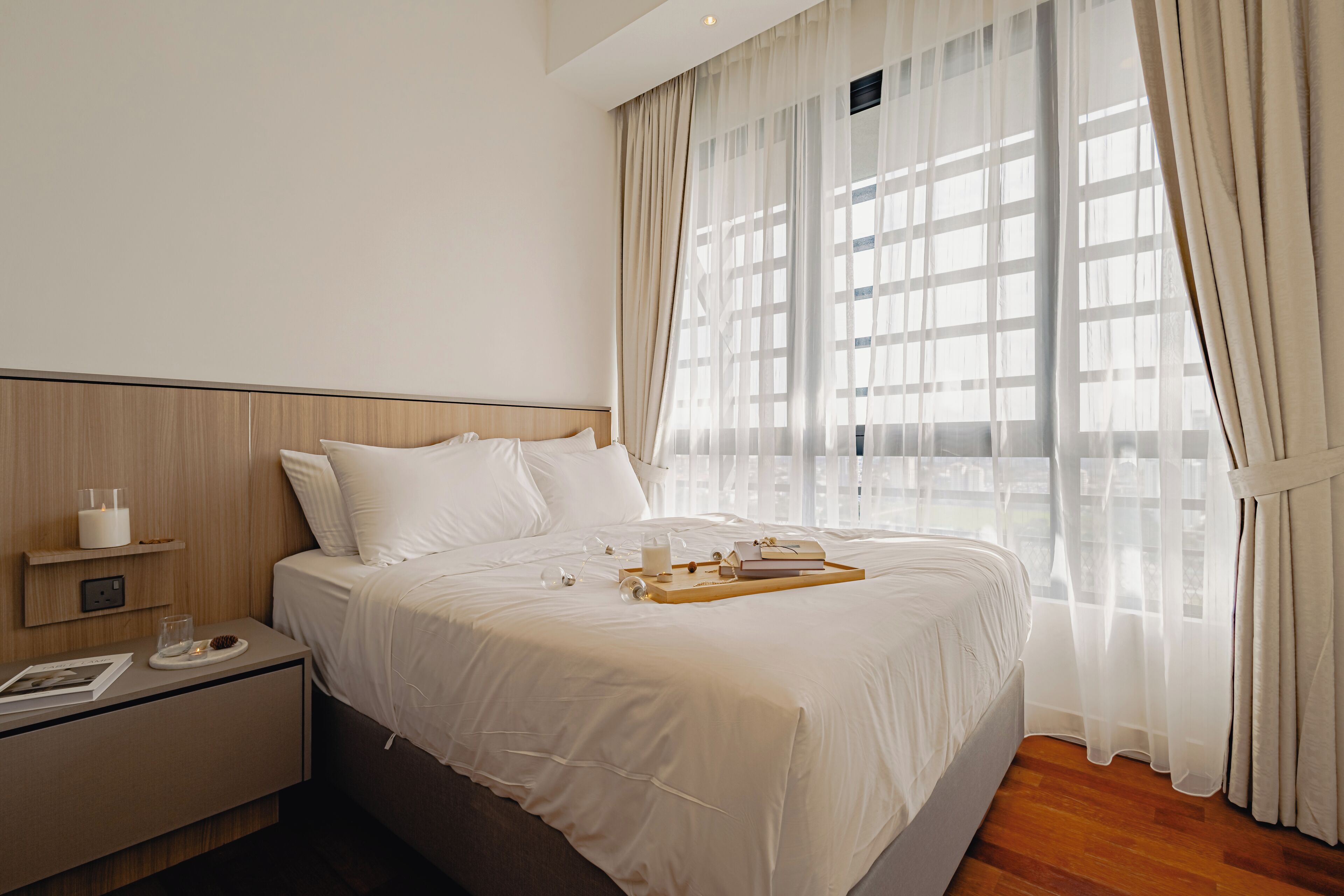 Una habitación de hotel moderna con una cama grande, una mesita de noche y cortinas traslúcidas.