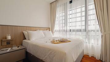 Una habitación de hotel moderna con una cama grande, una mesita de noche y cortinas traslúcidas.