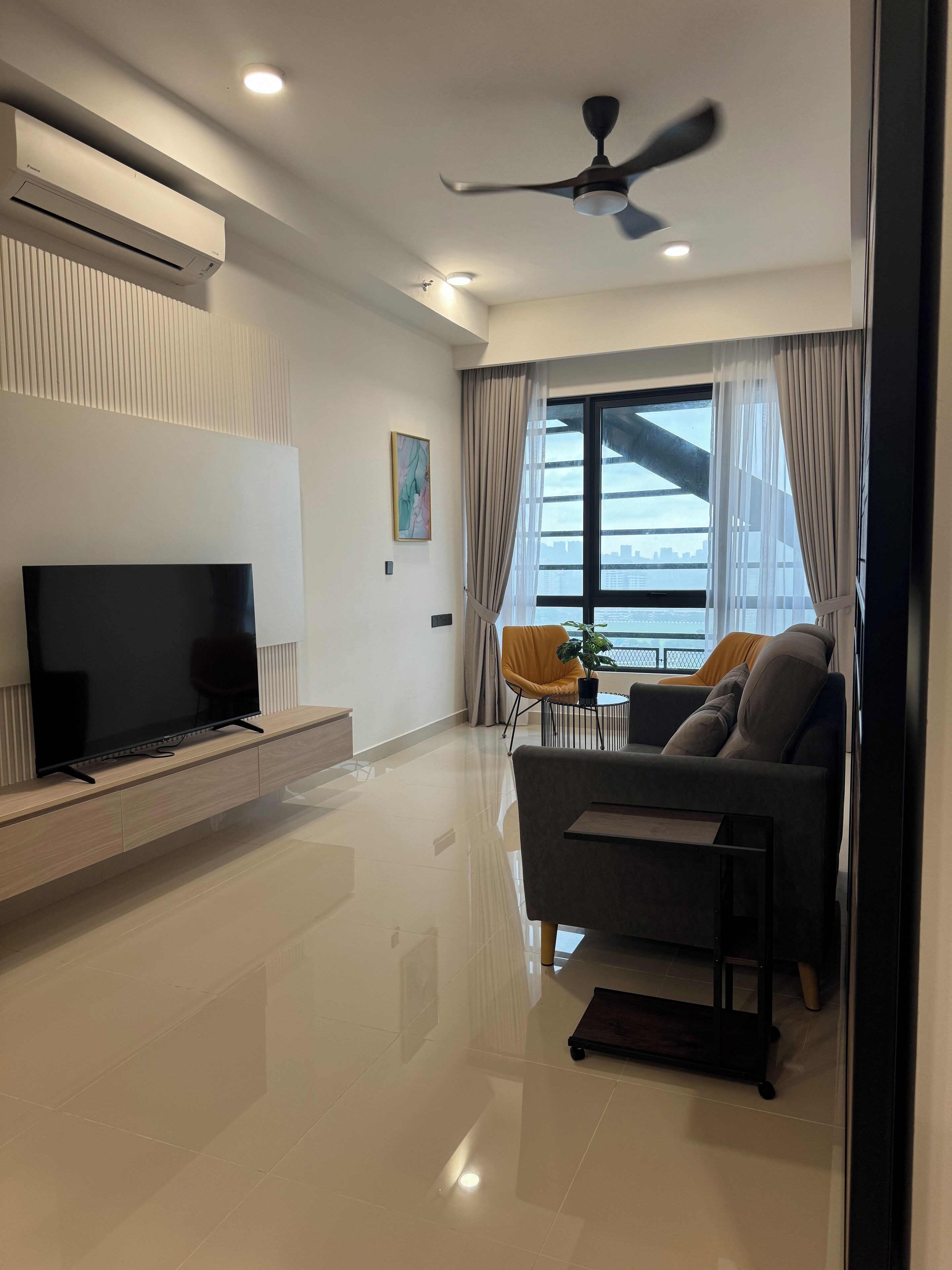 A modern living room with a flat-screen TV, a ceiling fan, and a sofa.