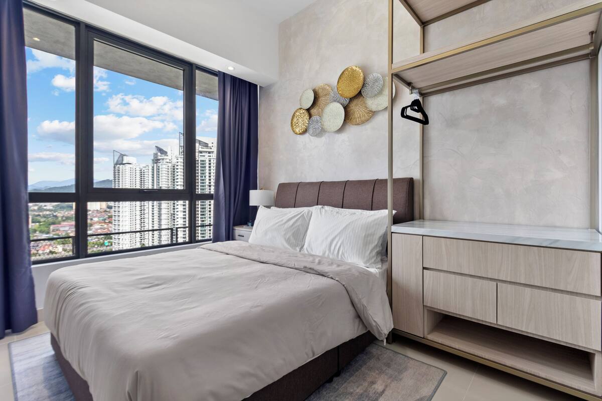 Une chambre moderne avec un grand lit, une table de chevet, une commode et un porte-manteau fixé au mur.